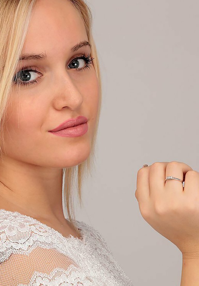 Silberner Ring mit filigranem Design, der an der rechten Hand getragen wird. Das Model hat lange blonde Haare, einen hellen Hautton und dezentes Make-up.