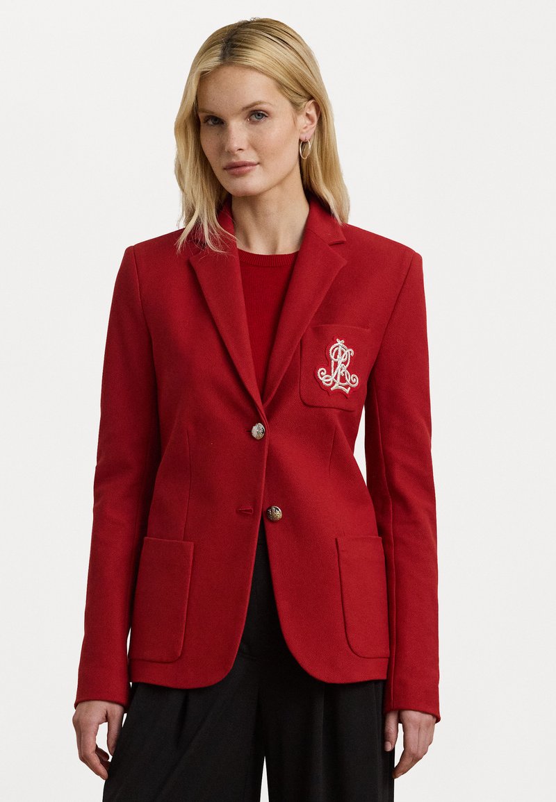 Blazer rouge en tissu texturé, doté de deux poches avant, de boutons dorés et d'un logo brodé sur la poche de poitrine gauche.
