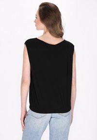 Sort top med korte ærmer, afslappet pasform og rund halsudsk�æring. Indsamlet kantdetalje. Bæres med lyseblå jeans. Enkelt og alsidigt design.