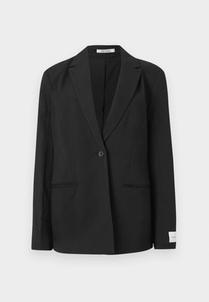Blazer noir avec un col cranté, fermeture à un bouton, deux poches avant et un badge rectangulaire sur la manche. Texture de tissu lisse.