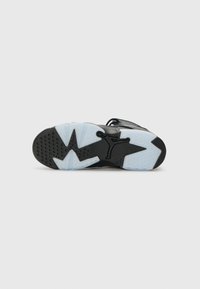Semelle de chaussure noire avec une section translucide bleu glacé, dotée d'un motif en forme d'étoile et du logo Jumpman. Points de traction texturés inclus.