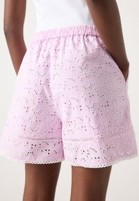 Rosa bomullsshorts med et strukturert blomstermønster og broderte detaljer, med en sammensunken elastisk midje og blonderkant på kanten.