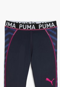 Leggings atletici navy con una fascia in bianco e nero "PUMA", dettagli rosa e un motivo a zigzag blu sul lato. Tessuto elasticizzato.