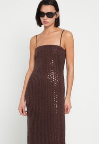Καφέ φόρεμα με παγιέτες, λεπτές τιράντες και εφάπαξ σιλουέτα, με κάθετες γραμμές λαμπερών παγιετών και λεία υφή.