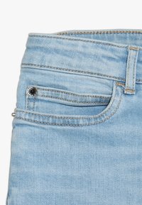 Ljusblå denimjeans med en klassisk femfickdesign, metallknappstängning och kontrasterande sömmar på texturerad tyg.