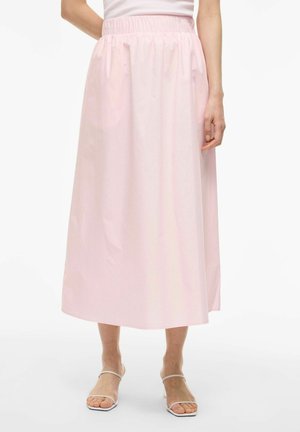 Femme portant une jupe midi rose clair avec une taille élastique, associée à des sandales blanches à lanières et un haut blanc.