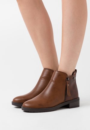 Bottines en cuir marron avec un panneau latéral texturé, fermeture éclair sur le côté et talon bloc. Fini lisse avec une semelle durable.