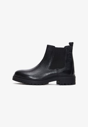 Bottines Chelsea en cuir noir avec finition texturée, panneaux latéraux élastiques, tirette et semelle en caoutchouc robuste avec motif à crampons.