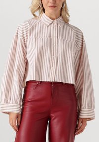 Gekraagde cropped shirt met witte en roze verticale strepen, knoopsluiting aan de voorkant en gepofte lange mouwen, gecombineerd met rode leren broek.