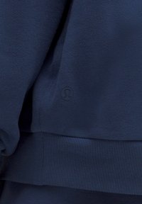 Felpa blu navy realizzata in tessuto morbido, con orlo e polsini a costine. Dettaglio del logo visibile nell'angolo in basso a sinistra.