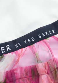 Tessuto floreale rosa con un sovrapposto trasparente, presenta una parte superiore bianca e una vita blu navy etichettata "by TED BAKER". Pieghe sottili all'orlo.