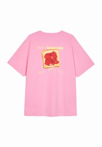 Rozā īsroku T-krekls ar grafiku, kurā attēlots grauzdiņš ar sarkanu ievārījumu un dzeltenu tekstu "IEBAUDI maizes dienu, tā ir visa jēga."