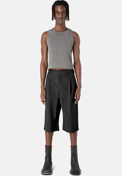 Top de tirantes gris cortado con textura acanalada, combinado con pantalones cortos negros holgados y botas negras hasta el tobillo. Diseño sencillo con un nivel mínimo de detalles.