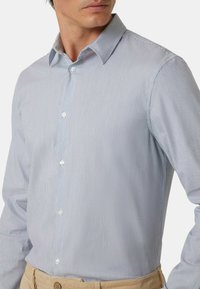 Camicia button-up a righe blu e bianche con colletto, caratterizzata da una texture liscia e piccoli bottoni bianchi rotondi lungo il davanti.