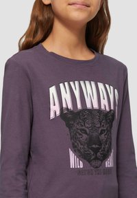 Paarse lange mouwen t-shirt met een luipaardafbeelding en "ANYWAYS" in vetgedrukte roze letters, tegen een zachte, gestructureerde stof.