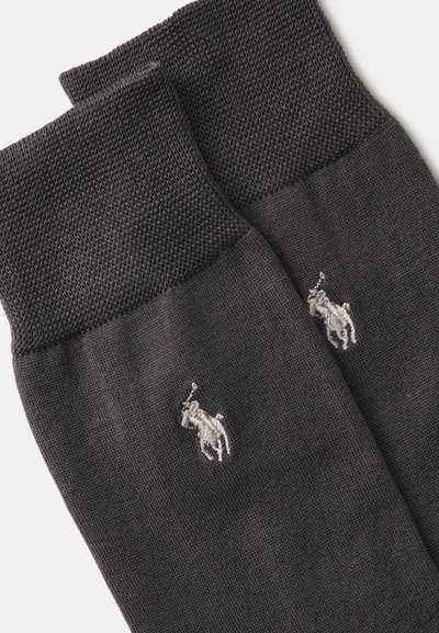 Meias pretas com uma faixa texturizada no tornozelo e corpo liso. Apresenta um pequeno logótipo em bordado de um jogador de polo prateado de cada lado.