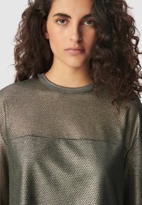 Metallisches Netzoberteil in Dunkelgrau, mit rundem Ausschnitt und langen Ärmeln, einem strukturierten Muster und leichtem Glanz.