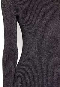 Haut en maille côtelée gris foncé avec éclat métallique. Comprend des manches longues et une coupe ajustée, mettant en valeur une texture verticale.