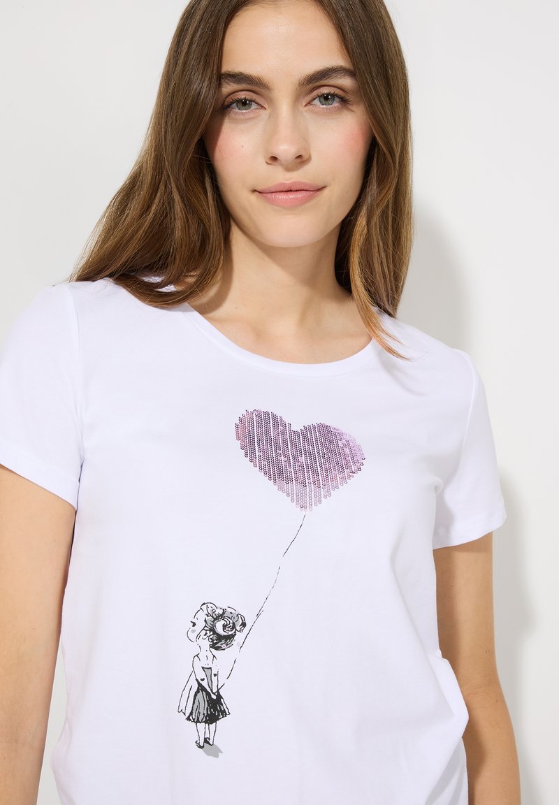 Weißes T-Shirt mit einer schwarz bedruckten Illustration eines Mädchens, das einen rosa herzförmigen Ballon hält, mit kurzen Ärmeln und Rundhalsausschnitt.