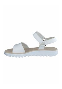 White sandals featuring a textured upper, wide toe strap, and adjustable back strap with a silver ring. Thick white rubber sole with a jagged edge.