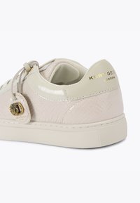 Jasnobeżowe sneakersy z wytłoczonym wzorem węża, błyszczącym wykończeniem, kremowymi akcentami, złotymi detalami i teksturowaną gumową podeszwą dla lepszej przyczepności.