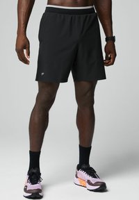 Schwarze Sport Shorts mit einem elastischen Bund, ausgestattet mit einem kleinen Logo am linken Bein und einer leichten, glatten Textur.
