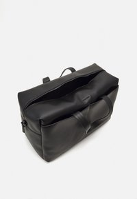 Borsa da viaggio in pelle nera con apertura superiore con cerniera, manici doppi e texture liscia. Presenta un design minimalista e senza hardware visibile.