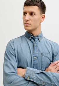 Hellblaues Jeanshemd mit Button-Down-Kragen, Brusttasche und silbernen Knöpfen. Verfügt über lange Ärmel und eine lockere Passform.