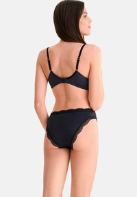 Ensemble de lingerie noire comprenant un soutien-gorge légèrement rembourré avec des bretelles ajustables et une culotte taille haute assortie, rehaussée de dentelle.