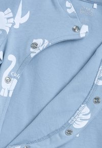 Ljusblå baddräkt med vita djur- och bladmönster, med tryckknappstängning fram och en mjuk, strukturert yta.