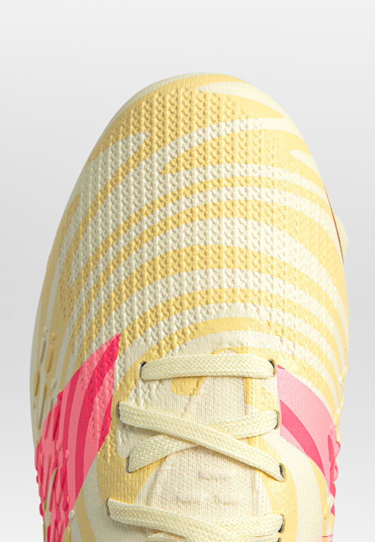 Geel sportieve schoen met gestructureerd materiaal, roze accenten en een golfpatroon design. Bevat veters en een gevormd oppervlak voor grip.