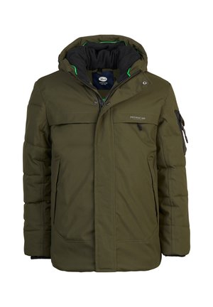 Personne portant une doudoune à capuche de couleur vert olive, une chemise beige clair, un jean bleu et des bottines marron à lacets, debout devant un fond gris.