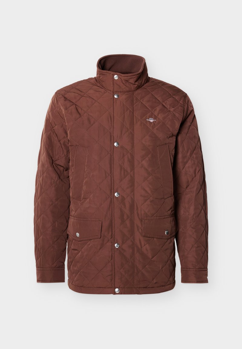 Veste marron matelassée avec un col montant, fermeture à boutons-pression et deux poches poitrine. Tissu lisse avec un motif en losanges et des accents argentés.