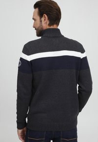 Maglione in maglia grigio carbone con colletto alto, caratterizzato da strisce orizzontali bianche e navy sulla schiena, polsi e orlo a coste.