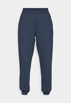 Mørkeblå joggebukser laget av myk, teksturert stoff, med elastisk liv med snøring, avsmalnende mansjetter og en subtil logo på venstre lår.