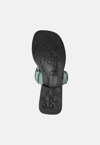 Svart gummisula på sandalen med upph�öjd text "CAM" och "PER". Grön tygrem vid hälen, storlek 38 präglad på sulan. Strukturerad yta.