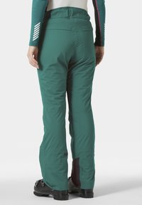 Groene geïsoleerde skibroek met een gladde textuur, voorzien van een contourede tailleband en contrasterende donkere accenten bij de enkels.