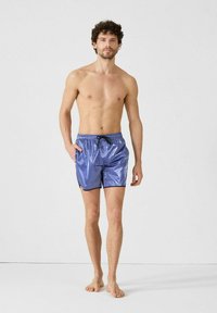 Blauwe, glanzende zwemshorts met een trekkoord in de taille, zijzakken en contrasterende zwarte accenten bij de beenopeningen.