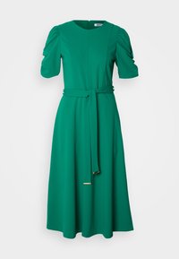 Πράσινο φόρεμα μέχρι το γόνατο από λεία ύφανση. Διαθέτει κοντά φουσκωτά μανίκια, εφαρμοστό μέση με ταιριαστό ζωνάκι και στρογγυλή λαιμόκοψη.