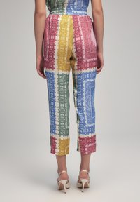 Pantalones estampados coloridos con un corte holgado, que presentan franjas alternas de rojo, verde, azul y amarillo, con una textura sedosa. Longitud por la mitad de la pantorrilla.