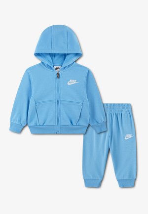 Lyseblåt todelt babytøjssæt med lynlåsfunktion, hættetrøje og bukser med elastisk talje, begge med hvidt Nike-logo.