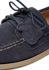 Marineblaues Wildlederschuhwerk mit einer braunen Gummisohle, dekorativem Stich und einer genähten Akzent mit einem lächelnden Charakter auf der Seitenpaneel.