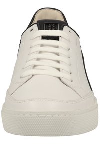 Baskets en cuir blanc avec des accents noirs, bout arrondi, lacets plats, semelle en caoutchouc texturée et une étiquette de marque sur la languette.