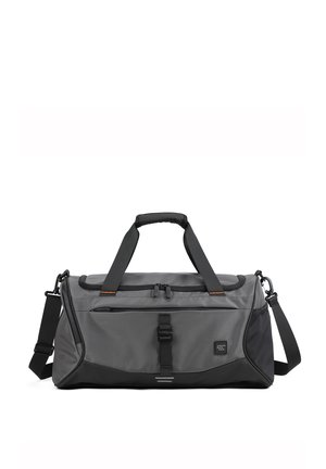 Sac de sport gris en tissu durable, doté d'une fermeture zippée, de deux poignées, d'une sangle réglable et d'accents noirs, avec une poche latérale.