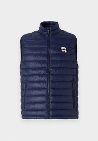 Navyblauwe gewatteerde vest met een hoge kraag, rits aan de voorkant en zijzakken. Heeft een horizontaal gestikt ontwerp en een klein logo detail.