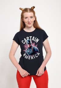 Sort t-shirt med et stort grafik af Captain America og teksten "CAPTAIN AMERICA" i hvid, iført med røde bukser.