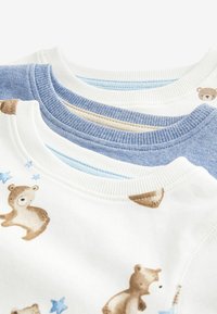Drei Rundhals-Sweatshirts in Weiß, Hellblau und Beige. Das weiße Sweatshirt hat ein Bärenmuster sowie gerippte Bündchen und einen gerippten Halskragen.