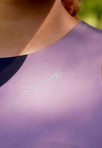 Lila Textilie mit glatter Oberfläche, mit einem schwarzen Akzent am Ausschnitt und dem Wort "Normal", das entlang des Stoffes aufgedruckt ist.