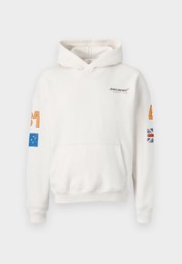 Moleton branco com capuz ajustável; possui o logótipo da McLaren, números laranja nas mangas, design de bandeira azul e um detalhe da bandeira britânica.