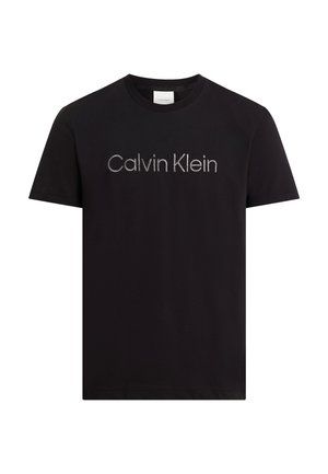T-shirt en coton noir à manches courtes, arborant un logo "Calvin Klein" argenté centré dans une police moderne. Texture lisse, coupe standard.